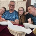 Pięć osób pozuje do zdjęcia przy nakrytym białą zastawą restauracyjnym stole. Dwaj mężczyźni mają na sobie takie same niebieskie t-shirty w motywy morskie z ośmiornicami.