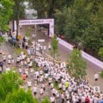Widok z góry na trasę i bramę z napisem „Sztafeta Pomocy Poland Business Run 2025” otoczoną przez grupy startowe uczestników.
