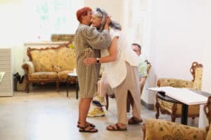 Maria Pietrusza-Budzyńska i Sonia Wilk ściskają się serdecznie. Sonia Wilk trzyma w ręku papierowy kwiat.