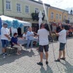 Agnieszka Gruszecka-Sędłak, kierownik Warsztatu Terapii Zajęciowej, udziela wywiadu podczas wydarzenia w Chełmie. Obok obserwują ją Tomasz Karenko i Anna Karaś, a nagranie realizują kamerzyści. W tle stoi wóz strażacki.