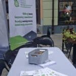 Stoisko Fundacji Centrum Niepełnosprawnych Przedsiębiorców prezentuje rollup informacyjny oraz kolorowanki „Kolorujemy różnorodność: Niepełnosprawność w kolorach” autorstwa Łukasza Kufty ułożone na stole.