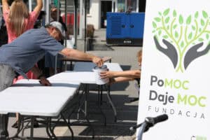 Mężczyzna wrzuca datek do puszki Fundacji „PoMOC Daje MOC”.