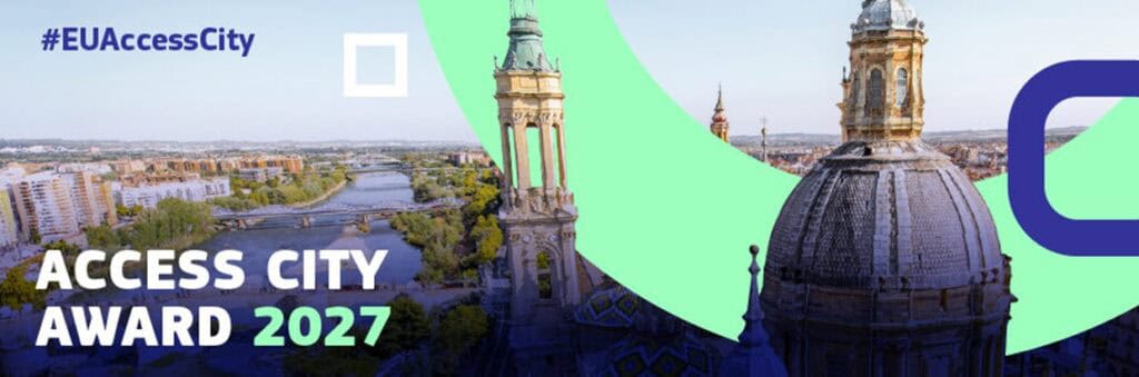 Baner promujący konkurs Access City Award 2027. Na tle panoramy miasta z rzeką, mostami oraz zabytkowymi wieżami i kopułą widoczne są zielone i granatowe elementy graficzne. W lewym górnym rogu znajduje się napis „#EUAccessCity”, a w dolnej części duży biało-zielony napis „ACCESS CITY AWARD 2027”.