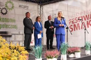 Anna Augustyniak, Małgorzata Romanko, Piotr Breś i Zbigniew Wojciechowski stoją na scenie ozdobionej wrzosami. W tle znajduje się baner organizatora ROPS Lublin.