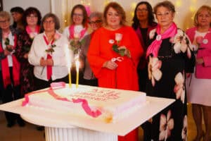 Uczestniczki jubileuszu stoją wokół dużego, prostokątnego tortu z napisem „35 lat Lubelskich Amazonek”. Na torcie palą się fontanny iskrowe.