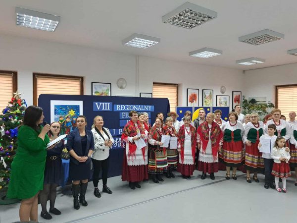 Zdjęcie grupowe; Pani Dyrektor Marzenna Karpowicz przemawia do ustawionych w półkolu artystów w strojach ludowych